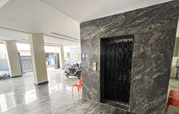 Lift area inside Casavir Mens PG Madhapur, marble-finish wall with iron elevator gate